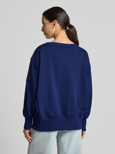Frauenmodel trägt Oversized Sweatshirt aus reiner Baumwolle Modell 'Wide Silver' von miss goodlife in Dunkelblau mit Ziernähten, elastische Abschlüsse, lockere Passform, Jeans kombiniert, Ganzkörperansicht Rückansicht.