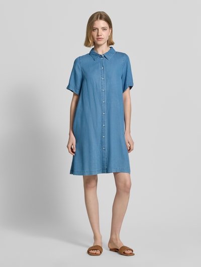 Frauenmodel trägt Tailliertes Jeanskleid aus Lyocell Modell 'BREE' von Vero Moda in Denim-Optik, Mini-Länge, V-Ausschnitt, Knopfleiste, Kurzarm, Material Lyocell, Ganzkörperansicht von vorne.