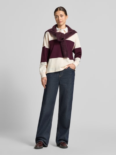 Frauenmodel trägt Regular Fit Sweatshirt aus reiner Baumwolle von GANT, breite Streifen in Creme und Dunkellila, blaue Jeans, Ganzkörperansicht von vorne.