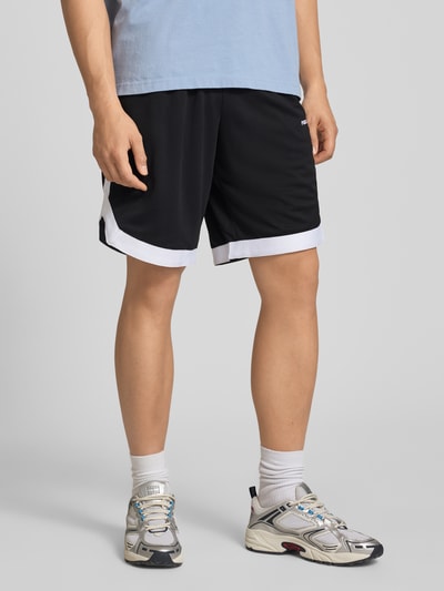 Männermodel trägt Relaxed Fit Shorts mit elastischem Bund von Pegador in Schwarz mit weißen Akzenten, Logo-Stitching, Eingrifftaschen, Ganzkörperansicht von vorne.