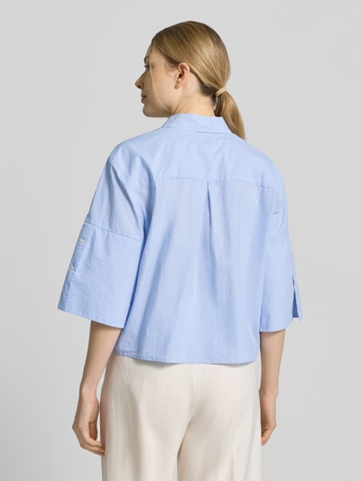 Frauenmodel trägt Boxy Fit Bluse aus Baumwolle mit Knopfleiste von Emily Van den Bergh in Hellblau, Reine Baumwolle, Hemdblusenkragen, Rückenlänge bei Größe 36: 54 cm, Ärmellänge in 3/4-Ärmellänge, Boxy-Fit, Ganzkörperansicht Rückansicht.