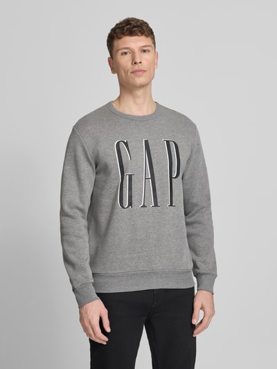 Mannelijk model draagt 'Sweatshirt met Logo' van GAP in grijs, katoenmix, regular fit, ronde hals, logoprint, ruglengte maat M 70 cm, mouwlengte maat M 67 cm. Ganzkörperansicht van voren.