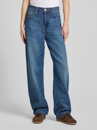 Frauenmodel trägt Tapered Fit Jeans im 5-Pocket-Design von Carhartt Work In Progress aus reiner Bio-Baumwolle, Bundweite 38 cm, Innenbeinlänge 78 cm, kräftiges Blau mit leichter Waschung, strukturierte Oberfläche, Ganzkörperansicht von vorne.