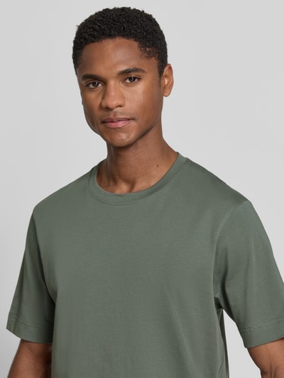 Männermodel trägt Slim Fit Poloshirt mit V-Ausschnitt Modell 'Braian' van Drykorn van puur katoen met structuurpatroon in groen, nahaufnahme oberkörper. Ruglengte maat M: 70 cm.