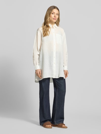Frauenmodel trägt Relaxed-Fit Longbluse aus Leinen Modell 'TAHIA' von 0039 Italy in Creme mit Hemdblusenkragen, Knopfleiste, Brusttasche, locker fallende Textur, Rückenlänge 86 cm, Ärmellänge 58 cm, Ganzkörperansicht von vorne.