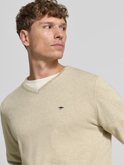 Männermodel trägt Strickpullover mit Label-Strickerei von Fynch-Hatton in Beige mit V-Ausschnitt und gerippten Abschlüssen, Nahaufnahme Oberkörper