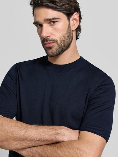 Männermodel trägt Regular Fit Strick-Shirt aus reiner Schurwolle Modell 'H-UMAURO' von BOSS, unifarben, kurzarm, Nahaufnahme Oberkörper.