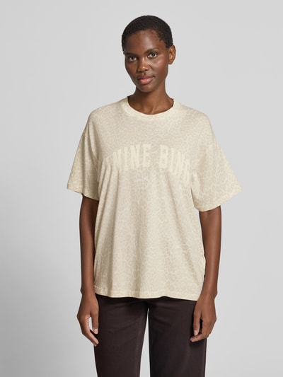 Frauenmodel trägt Oversized T-Shirt mit Logo-Print von Anine Bing aus reiner Baumwolle, Allover-Animal-Print, Rundhalsausschnitt, Oversized-Fit, Rückenlänge bei Größe S 64 cm, cremefarben mit hellen Tiermuster-Texturen, Ganzkörperansicht von vorne.