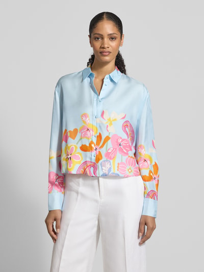 Vrouwenmodel draagt Boxy Fit Bluse aus Seide im Allover-Look van HERZENS in lichtblauw met kleurrijke bloemenprint, recht silhouet, hemdkraag, knoopsluiting, pure zijde, ruglengte 58 cm, mouwlengte 60 cm, vooraanzicht volledige lichaamsopname.