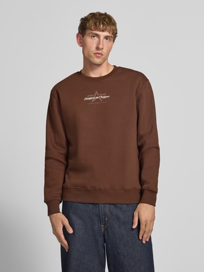 Männermodel trägt Regular Fit Sweatshirt aus Baumwoll-Mix mit Label-Detail von Alpha Industries, braun, elastische Abschlüsse, Ganzkörperansicht von vorne.