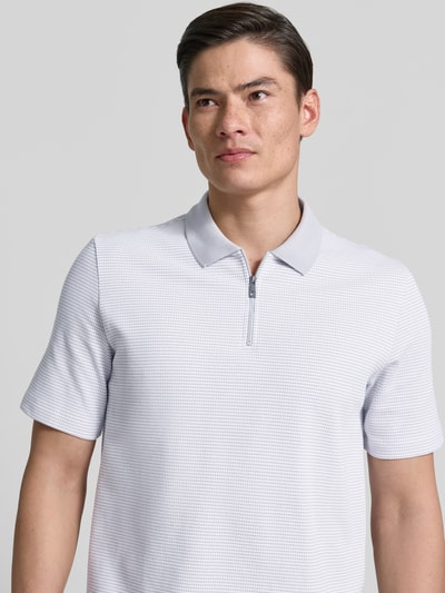 Męski model nosi Regular Fit Poloshirt mit Reißverschluss od MAERZ Muenchen, dwukolorowa faktura, wzór strukturalny, zamek, ujęcie z przodu zbliżenie górnej części ciała.