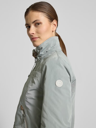 Vrouwenmodel draagt Jacke mit Kapuze und Reißverschlusstaschen van Gil Bret in regular fit, lichtgrijs, detailopname bovenlichaam, kap met tunnelkoord, opstaande kraag, ritssluiting, ritszakken, ruglengte maat 36: 59 cm, schouderbreedte: 40 cm, borstwijdte: 51 cm, mouwlengte: 63 cm.