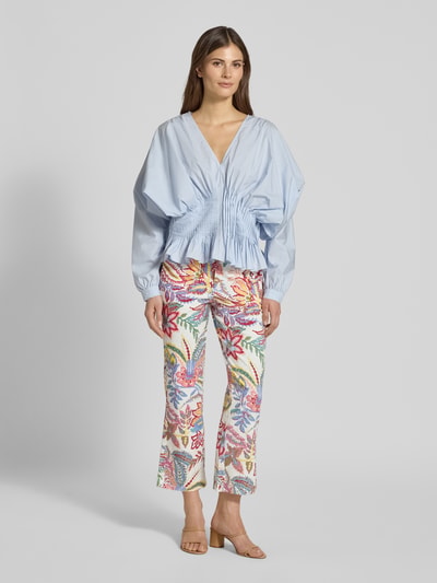 Modelka nosi Caprihose im Allover-Look von Milano Italy w kolorowy, kwiatowy wzór, bawełna z elastanem, krój flared cut, boczne kieszenie, szerokość w rozmiarze 36: 37 cm, długość nogawki wewnętrznej 67 cm, widok całej sylwetki z przodu.