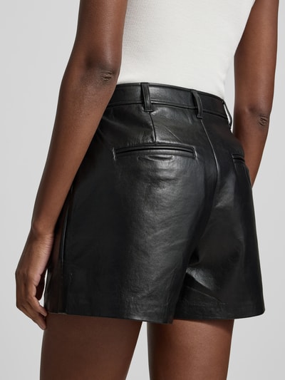 Frauenmodel trägt Shorts mit Leder-Anteil von Anine Bing in Schwarz, Material-Mix, Eingrifftaschen, ausgestellte Passform, Detailaufnahme Rückenansicht.
