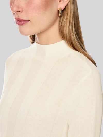 Frauenmodel trägt Strickpullover aus Schurwolle-Mix mit Stehkragen von Marc Cain, cremefarben, feine Struktur, Nahaufnahme Oberkörper, Damen Strickpullover, Slim Fit, Kaschmir-Anteil, Label-Detail, Rückenlänge 55 cm, Ärmellänge 66 cm.