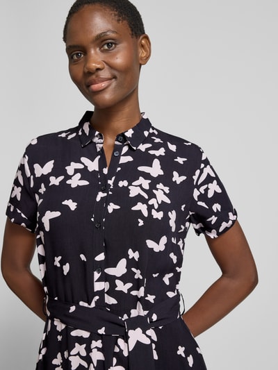Frauenmodel trägt Hemdblusenkleid im Allover-Look mit Bindegürtel von Christian Berg Woman Selection aus reine Viskose, Knopfleiste, taillierter Schnitt, Midikleid, Schwarz mit hellem Muster, Nahaufnahme Oberkörper.