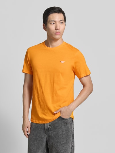 Männermodel trägt T-Shirt mit Logo-Patch und Rundhalsausschnitt von Emporio Armani in Orange, Reine Baumwolle, Modern Fit, Rückenlänge 69 cm, Ganzkörperansicht von vorne.