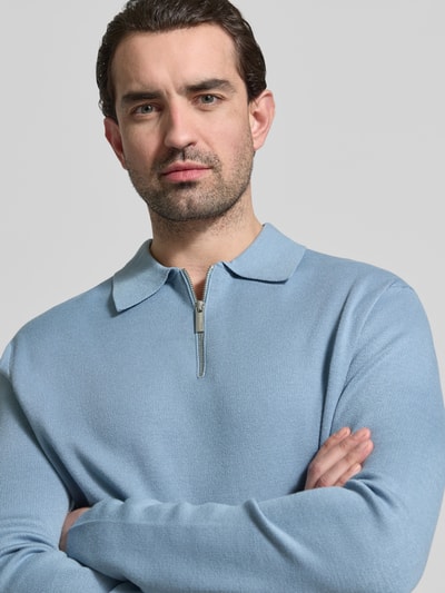 Männermodel trägt Relaxed Fit Pullover aus Viskose-Mix Modell 'TELLER' von SELECTED HOMME in Hellblau, Feinstrick, Nahaufnahme Oberkörper.