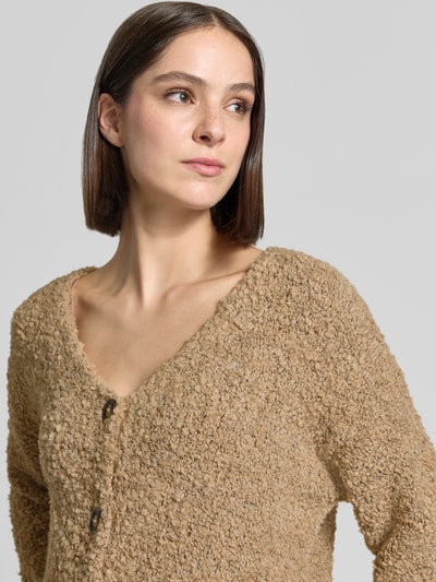 Frauenmodel trägt Relaxed Fit Strickjacke aus Woll-Viskose-Mix Modell 'Sofia' von ZABAIONE, beige Farben, V-Ausschnitt, Nahaufnahme Oberkörper.