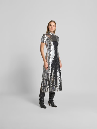 Frauenmodel trägt Maxikleid mit Allover-Zierbesatz von Self-Portrait in Silber, taillierte Passform, Stehkragen, Reißverschluss, kurzärmelig, glänzende, strukturierte Oberfläche, Gesamtlänge 133 cm, Brustweite 36 cm, Taillenweite 33 cm, Ärmellänge 15 cm, Ganzkörperansicht von vorne.