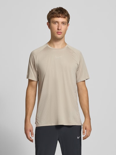 Männermodel trägt Regular Fit T-Shirt mit Aero-FIT-Technologie Modell 'STRIDE' von Nike in Beige, Herren Sport-T-Shirt, Ganzkörperansicht von vorne.