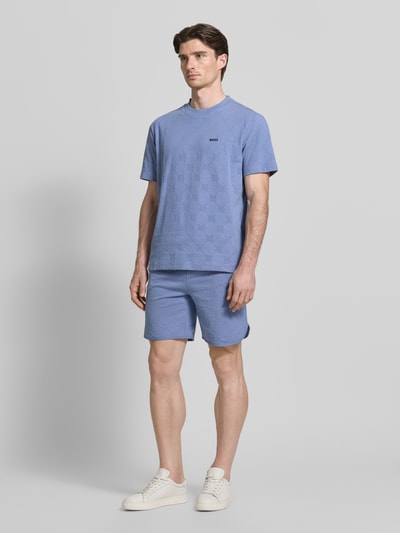 Männermodel trägt Regular Fit Shorts aus Baumwoll-Mix Modell 'JT_Member Short' von BOSS Green in Optik: Unifarben, grafisch strukturiert, mit Bundabschluss: elastisch, seitlichen Eingrifftaschen und angedeuteter Gesäßtasche, Materialverarbeitung: Sweat; hellblaue Farbgebung, glatte Textur, Ganzkörperansicht von vorne.