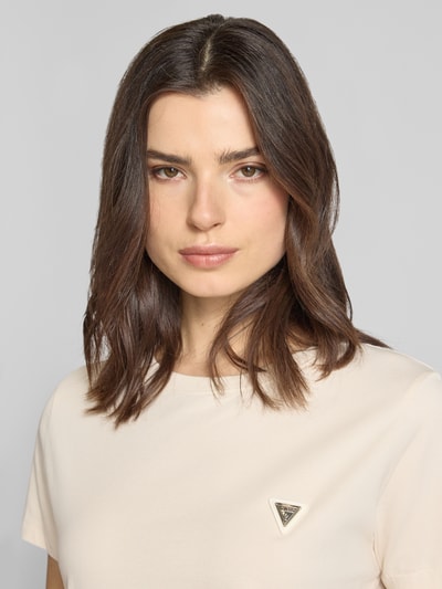 Modelka kobieca nosi Regular Fit T-Shirt mit Logo-Applikation Modell 'Colette' od Guess Activewear, kremowy, bawełna elastyczna, dekolt okrągły, długość tyłu w rozmiarze S: 60 cm, zbliżenie na górną część ciała