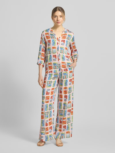 Frauenmodel trägt Relaxed Fit Stoffhose aus reiner Viskose von Milano Italy mit farbigem Print, Elastikbund mit Smok-Detail und Eingrifftaschen, Ganzkörperansicht von vorne.