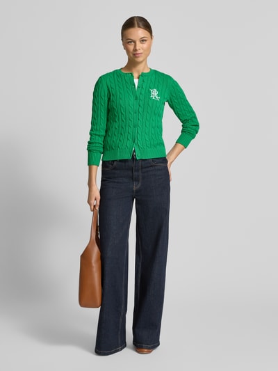 Frauenmodel trägt grüne Strickjacke mit Zopfmuster und Label-Stitching Modell 'RALHAN' von Lauren Ralph Lauren aus Baumwolle, Ganzkörperansicht von vorne.