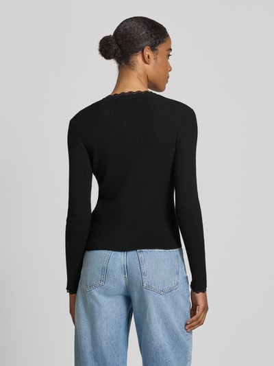 Frauenmodel trägt Slim Fit Strickjacke aus Viskose-Mix Modell 'Wonder' von Vero Moda, Optik: Unifarben, Rippstrick, Ganzkörperansicht Rückansicht.