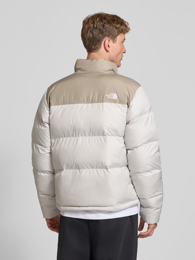 Männermodel trägt Regular Fit Jacke in Stepp-Optik Modell 'SAIKURU' von The North Face in Beige und Hellgrau, Rückenansicht, Nahaufnahme Rücken. Damen Jacke, Logo-Stitching, Stehkragen, Maße Größe M.