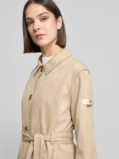 Frauenmodel trägt Trenchcoat mit Bindegürtel Modell 'CORDELIA' von Frieda & Freddies, beige, Material-Mix mit Stretch-Anteil, Nahaufnahme Oberkörper.