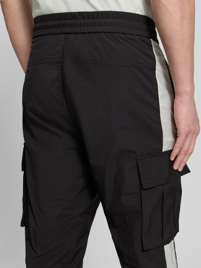 Männermodel trägt Regular Fit Cargohose mit Label-Applikation Modell 'COLAS262' von HUGO, Two-Tone-Optik, Twill, Nahaufnahme Rückansicht.