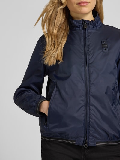 Frauenmodel trägt dunkelblaue Jacke mit Zweiwege-Reißverschluss Modell 'ANNABEL' von Blauer Usa, Stehkragen, Label-Details, Nahaufnahme Oberkörper.
