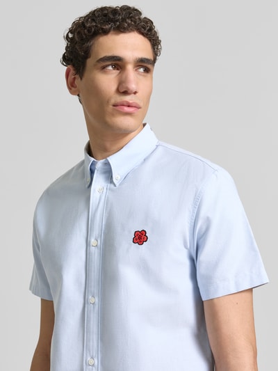 Männermodel trägt Slim Fit Freizeithemd mit Logo-Stitching von Kenzo aus reiner Baumwolle, Button-Down-Kragen, hellblau, Nahaufnahme Oberkörper.