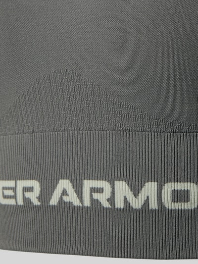 Detailaufnahme, productfoto, grijs oppervlak met structuur, wit logo-opschrift, Slim Fit SportBH met Logo-Print model 'Vanish' van Under Armour, elastische materiaalmix