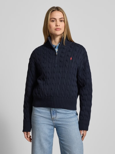 Vrouwenmodel draagt Troyer met Zopfstrickmuster van Polo Ralph Lauren, puur katoen, regular fit, kabelpatroon, opstaande kraag met ritssluiting, gestikt logo, elastische boorden, donkerblauw, voorkant geheel zichtbaar, Ganzkörperansicht von voren.