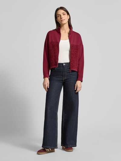 Frauenmodel trägt Regular Fit Sweatjacke mit Strickbesatz von Marc Cain in Bordeauxrot, Stehkragen, Baumwoll-Mix, Ganzkörperansicht von vorne.