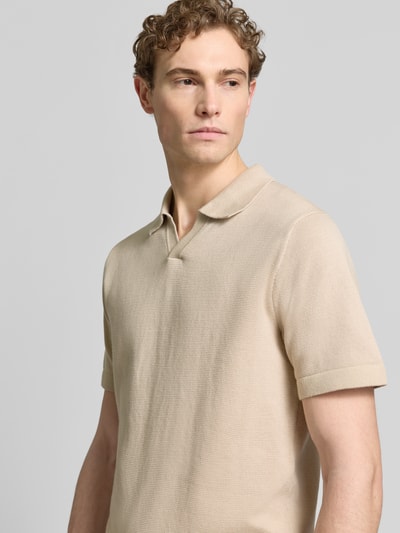 Mannelijk model draagt Strickshirt met V-hals model 'MILANO' van Jack & Jones Premium in beige met rechte fit, katoenmix, labeldetail, omgeslagen kraag, close-up bovenlichaam, voorkant.