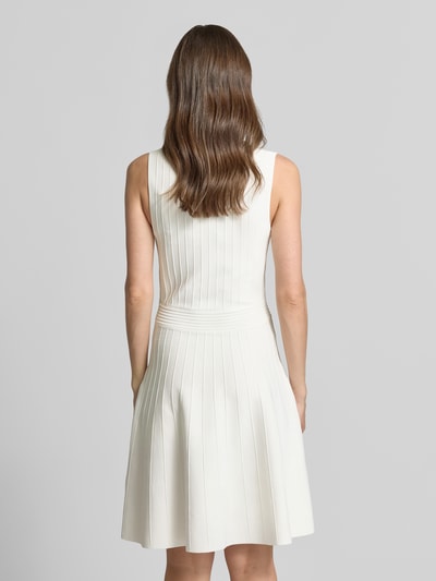Frauenmodel trägt knielanges Kleid aus Viskose-Mix Modell 'Amber' von Guess in Weiß mit Strick-Optik, tailliert, ärmellos, Rückansicht.