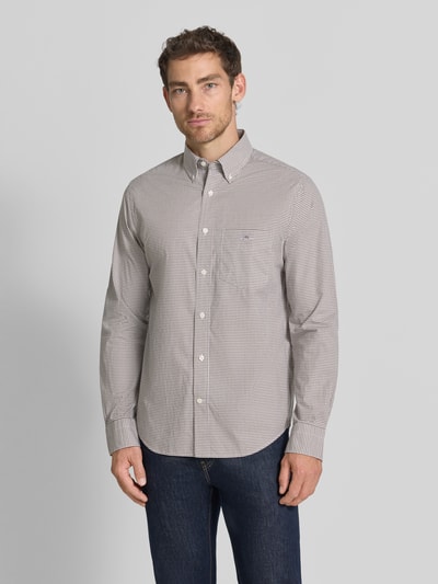 Männermodel trägt Regular Fit Freizeithemd aus reiner Baumwolle von GANT, feines Karo in Beige und Weiß, glatte Struktur, Ganzkörperansicht von vorne.