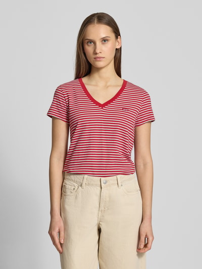 Modelka nosi T-Shirt mit V-Ausschnitt und Label-Stitching von Levi's®, bawełna, krój regular fit, V-neck, czerwone i białe paski, widok całej sylwetki z przodu.
