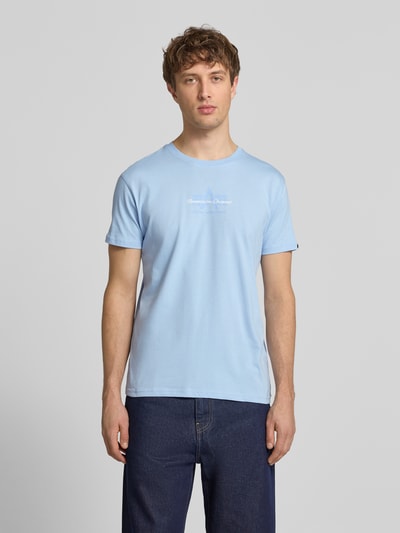 Męski model nosi T-Shirt mit Label-Detail von Alpha Industries, jasnoniebieski, bawełna, prosty krój, okrągły dekolt, długość tyłu 68 cm, Ganzkörperansicht von vorne