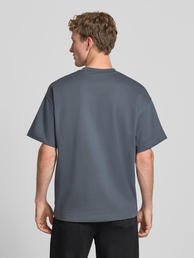 Männermodel trägt T-Shirt mit Rundhalsausschnitt Modell 'BARRON' von Jack & Jones in Grau, Baumwoll-Mix, Relaxed Fit, Rückenlänge 73 cm, Ganzkörperansicht Rückansicht.