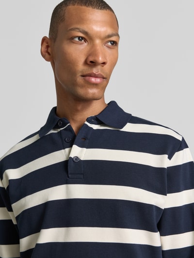 Männermodel trägt Regular Fit Poloshirt von Lindbergh in Dunkelblau mit weißen Streifen, Baumwoll-Materialmix, Nahaufnahme Oberkörper.