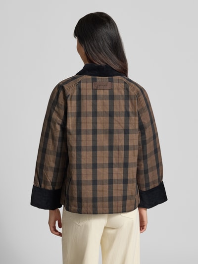 Frauenmodel trägt Regular Fit Hemdjacke mit Allover-Muster von GANT im karierten Braun- und Schwarztönen, Damen Parka, Ganzkörperansicht Rückansicht.