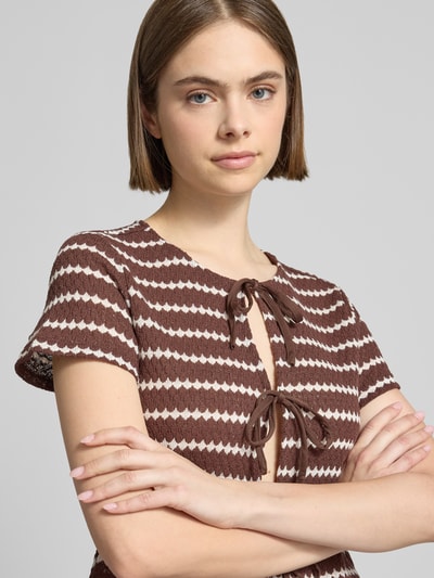 Kobiece model prezentuje Regular Fit Strick-Shirt mit Baumwoll-Anteil Modell 'EVA' od Only, efekt: wzór na całej powierzchni, okrągły dekolt, krótki rękaw, wiązane zapięcie, wykończenie: dzianina; zbliżenie na górną część ciała
