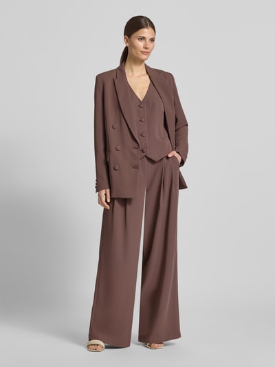 Kobiece model nosi Wide Leg Stoffhose mit Raffungen od Christian Berg Cocktail, elastyczna mieszanka materiałów, spodnie z szerokimi nogawkami, marszczenia, zapięcie na haftkę i zamek błyskawiczny, szerokość w rozmiarze 36: 38 cm, długość wewnętrzna nogawki w rozmiarze 36: 82 cm, kolor brązowy, gładka tekstura, widok całej sylwetki z przodu.