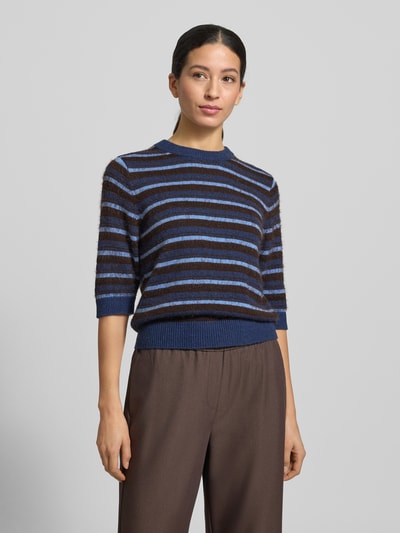 Modelka kobieca ma na sobie Strickpullover mit gerippten Abschlüssen od OPUS z bawełnianą mieszanką, krój slim fit, półrękaw, okrągły dekolt, paski w odcieniach niebieskiego i brązu, wykończenia prążkowane, długość tyłu w rozmiarze 36: 53 cm, długość rękawa: 31 cm, widok całej sylwetki z przodu.