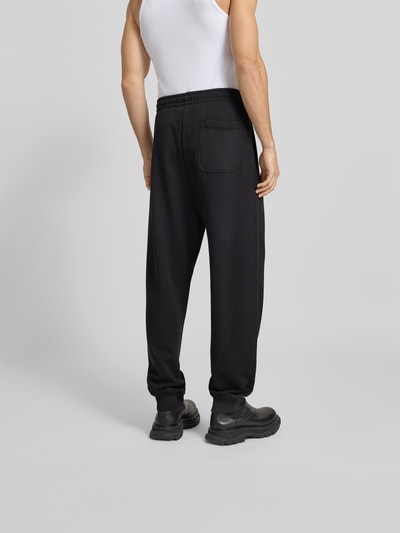 Männermodel trägt Sweatpants mit Label-Detail von Diesel aus reiner Baumwolle mit lockerem Schnitt, Gesäßtasche, Bundweite 42 cm, Ganzkörperansicht Rückansicht.